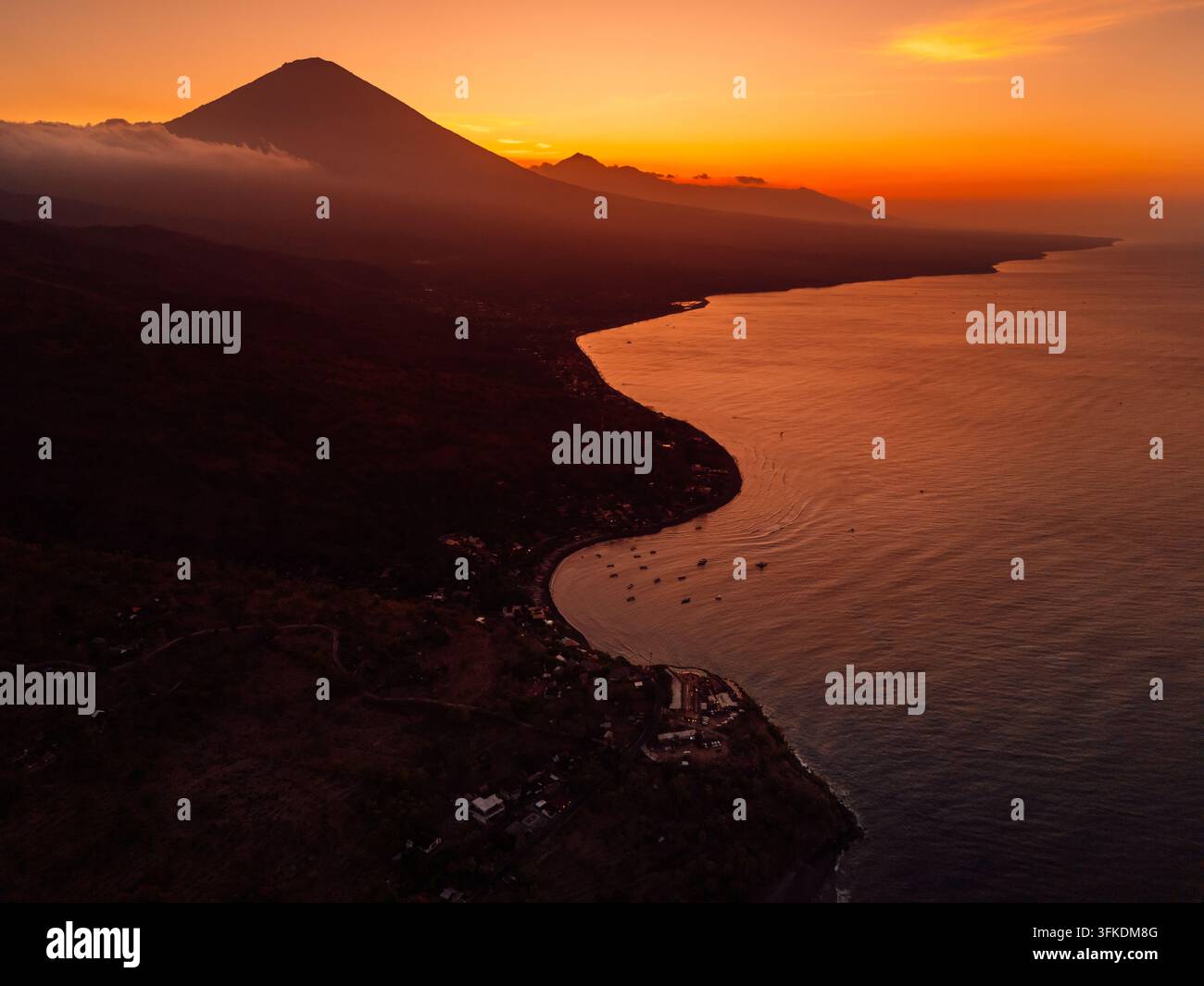 Tramonto dorato su un paesaggio costiero vulcanico con una montagna e un mare calmo Foto Stock