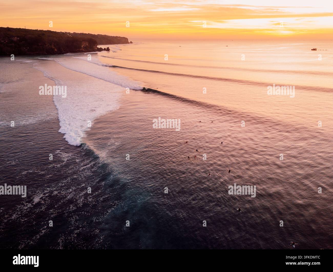 Vista aerea del tramonto su onde gentili che si infrangono su una costa tropicale Foto Stock