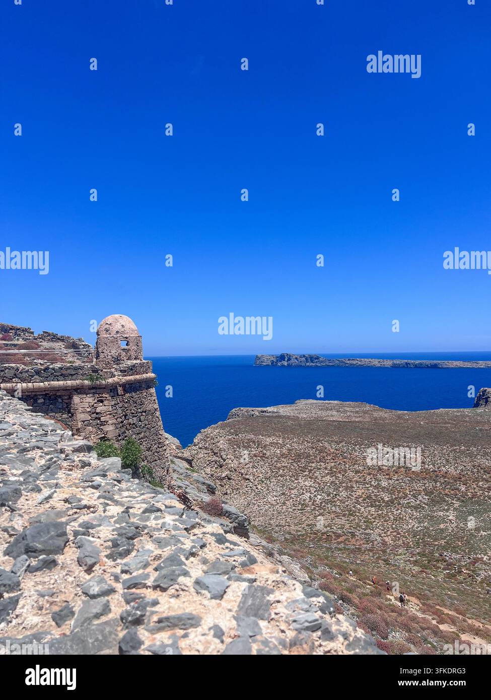 Il torrione della fortezza veneziana storica e le mura di pietra del forte di Gramvousa si affacciano sul mare blu profondo e sulla costa rocciosa di Creta, Grecia. - Immagine stock catturata con smartphone
