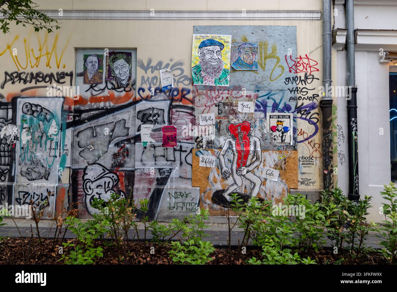 Graffiti a strati, poster e street art coprono un muro nel centro di Varsavia. Foto Stock