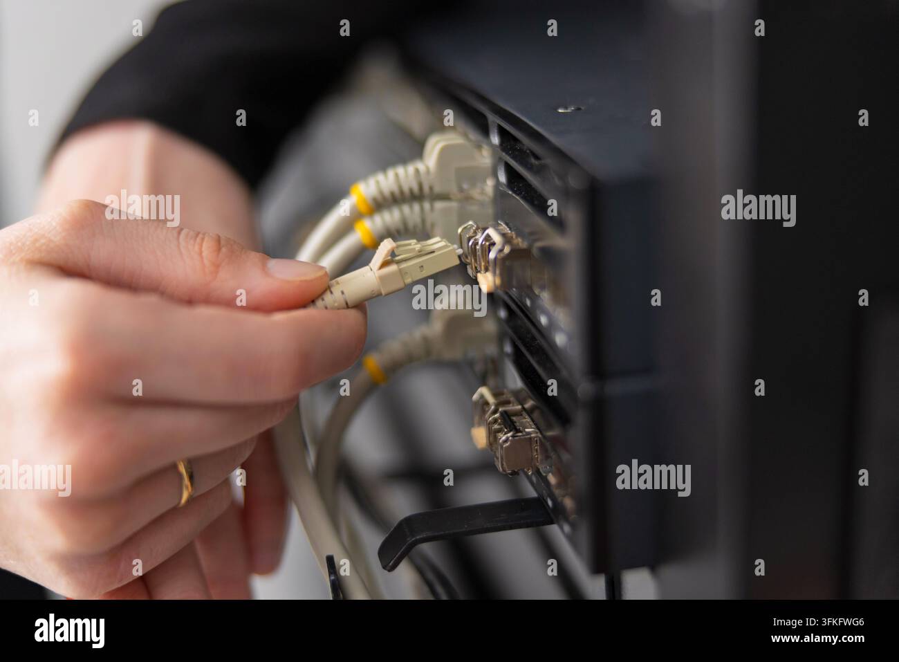 Tecnico informatico adulto mantiene il data center collegando cavi di rete a uno scaffale di server per la risoluzione dei problemi e gli aggiornamenti Foto Stock