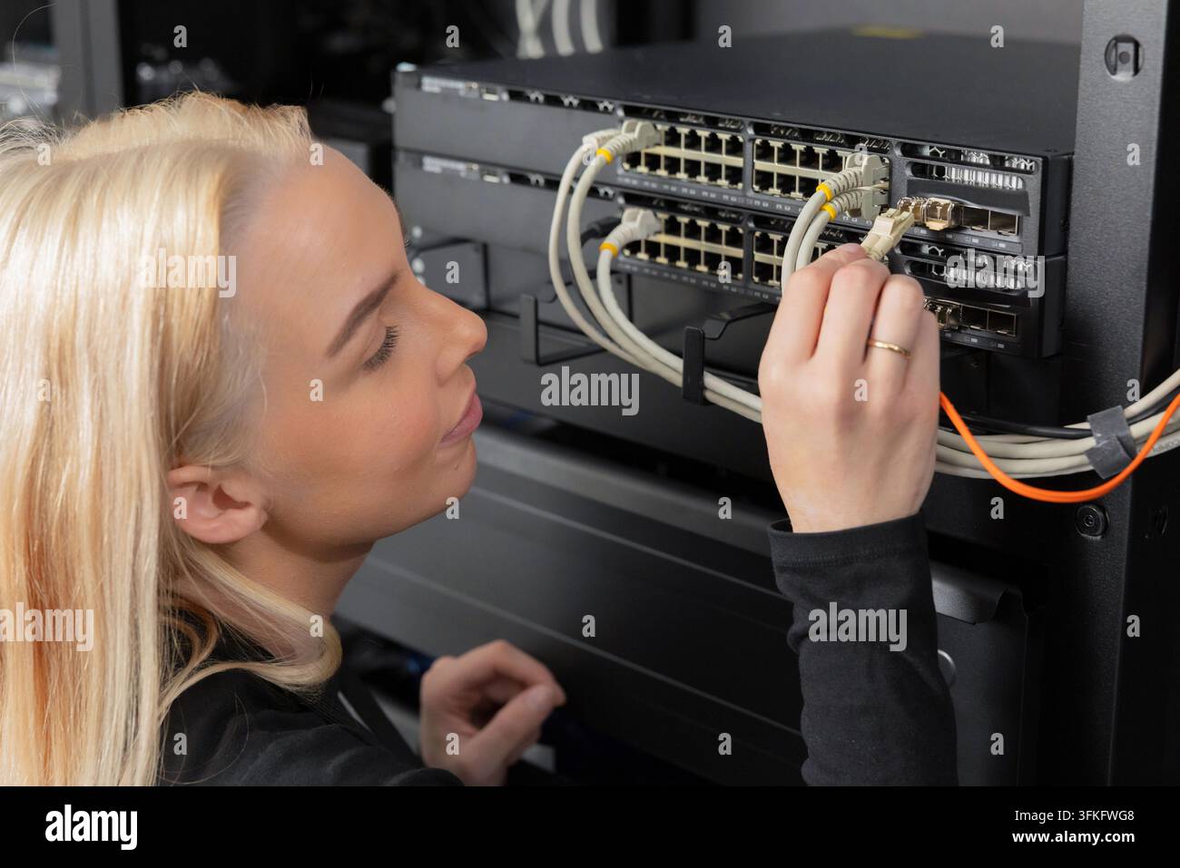 Tecnica IT in un data center mantiene e configura l'attrezzatura di rete dei server Foto Stock