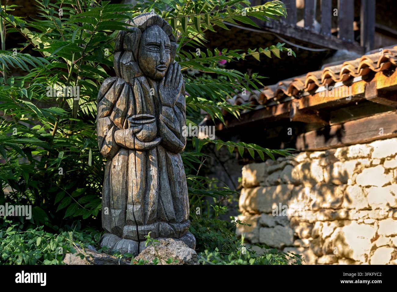 Statua in legno intagliata a mano di una figura che tiene una ciotola in preghiera, Casa del vino Radosavijevic, villaggio di Rogijevo, Serbia Foto Stock