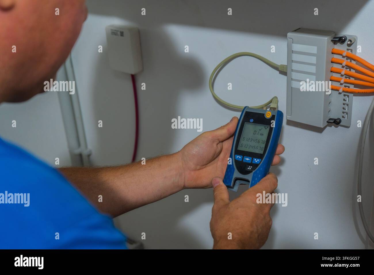 Tecnico che testa il cablaggio di rete con un tester portatile per cavi collegato a un pannello di connessione a Mühlheim am Main, Assia, Germania, fotografato il 13 agosto Foto Stock