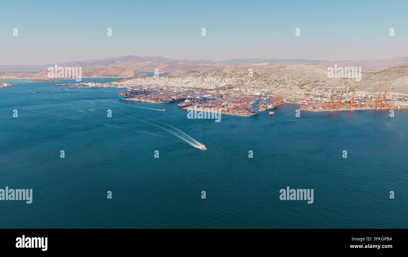 Il porto del Pireo mostra estese operazioni di navigazione globale con numerosi container di merci e gru, simboleggiando il commercio internazionale e la logistica Foto Stock