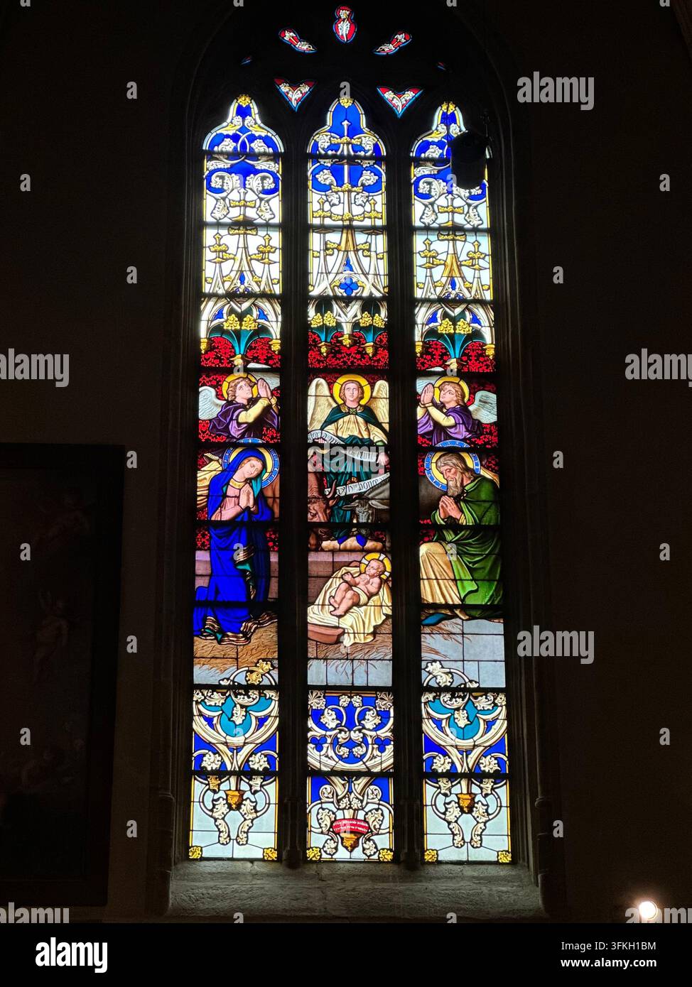 Vetro colorato vivace che raffigura la scena della natività in una chiesa. Vetrata policromata a pannelli multipli dettagliata all'interno di una cattedrale con motivi religiosi - Immagine stock catturata con smartphone