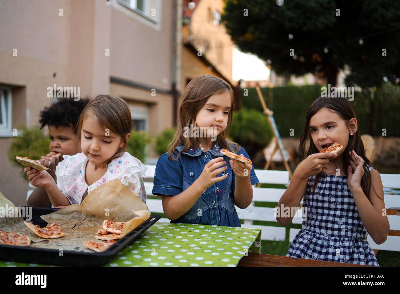 Bambini che mangiano mini pizze a una festa in giardino all'aperto Foto Stock