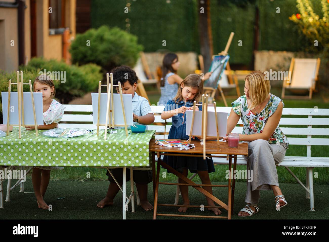 Bambini che imparano a dipingere all'aperto con l'insegnante durante la lezione di arte Foto Stock