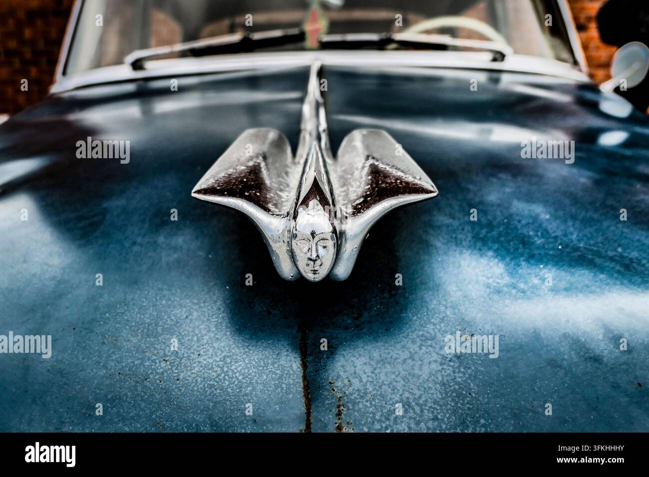 Primo piano di un ornamento cromato elaborato sul cofano di un'automobile vintage logorata Foto Stock