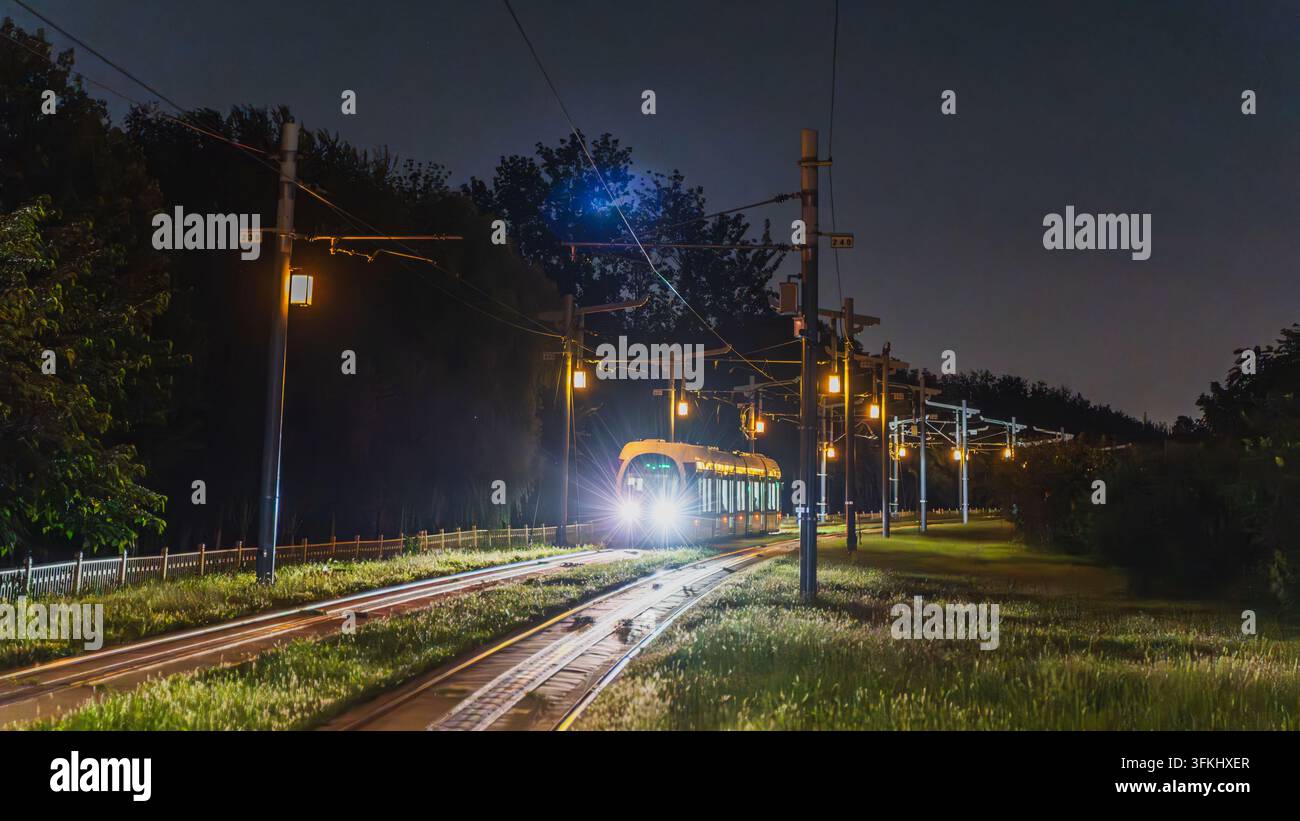 Tram che corre su binari di notte sulla linea suburbana ovest di Pechino Foto Stock