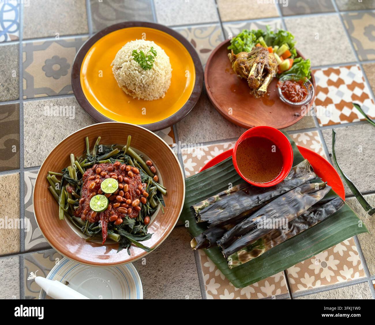 Nasi timbel indonesiano tradizionale con riso avvolto in foglie di banano, pollo fritto, verdure fresche e sambal piccante. Foto Stock