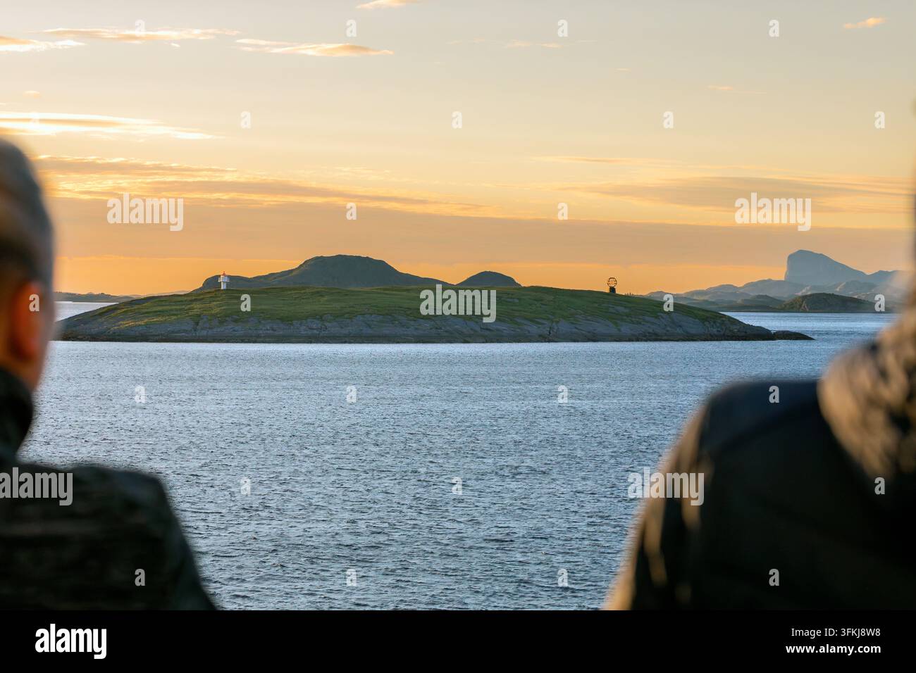 I passeggeri della nave osservano il monumento del globo sull'isolata isola di Vikingen nel Nordland, in Norvegia. Il monumento segna il circolo polare artico. Foto Stock
