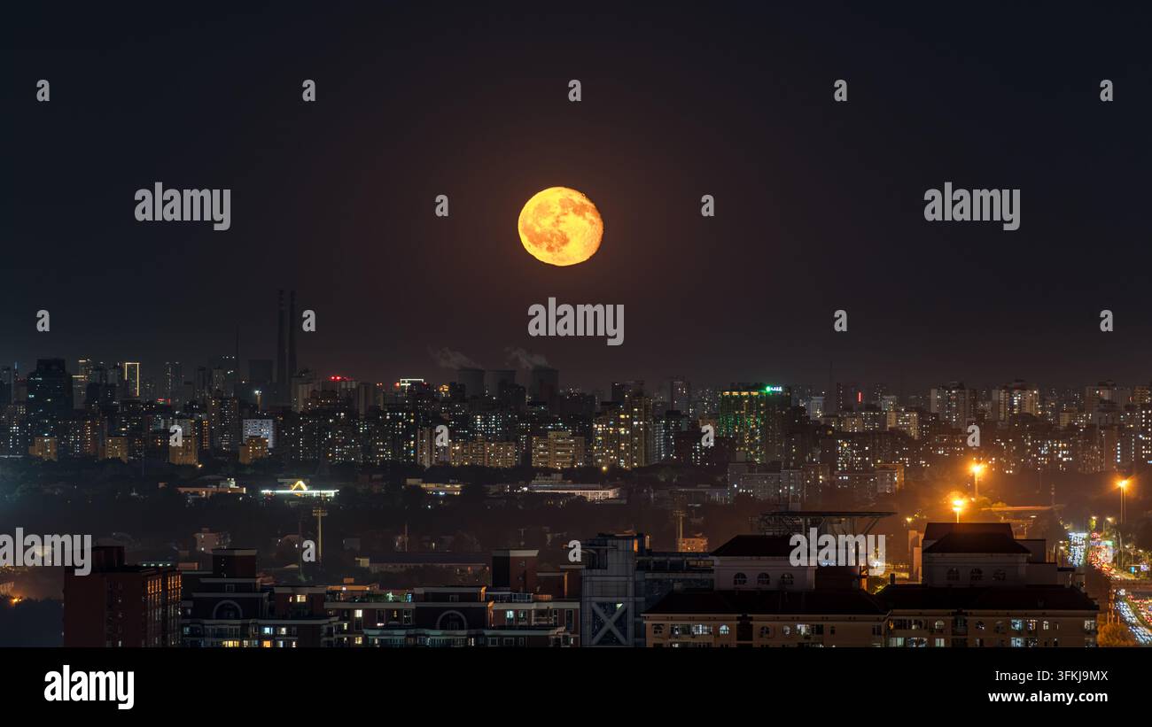 Luna piena sospesa sopra lo skyline della città di Pechino Foto Stock
