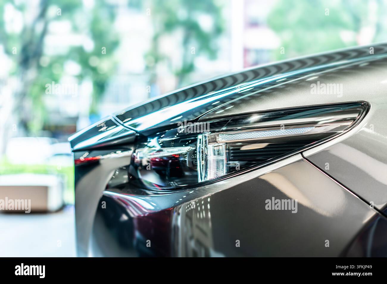Vista frontale di una nuova auto moderna argentata con fari a LED in uno showroom Foto Stock