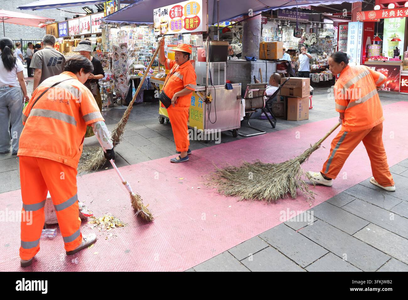 Addette alla pulizia delle strade al lavoro con scope di bambù antiquate a Xi'an, Cina Foto Stock