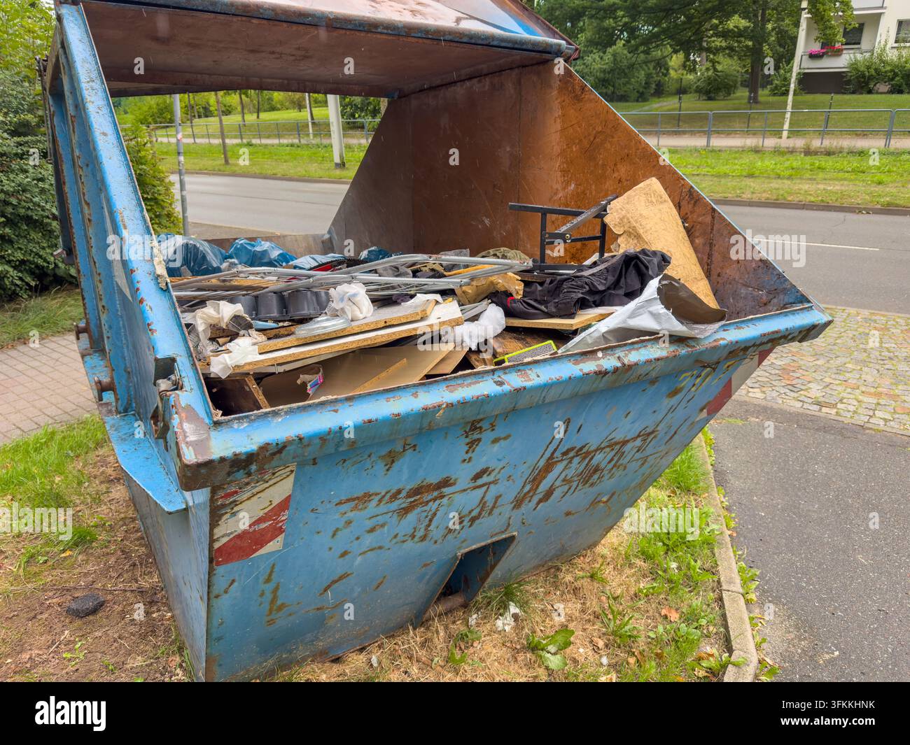 Grande contenitore pieno di oggetti domestici e mobili scartati dopo una svuotata di appartamento o casa. L'immagine rappresenta la raccolta dei rifiuti, dispo Foto Stock
