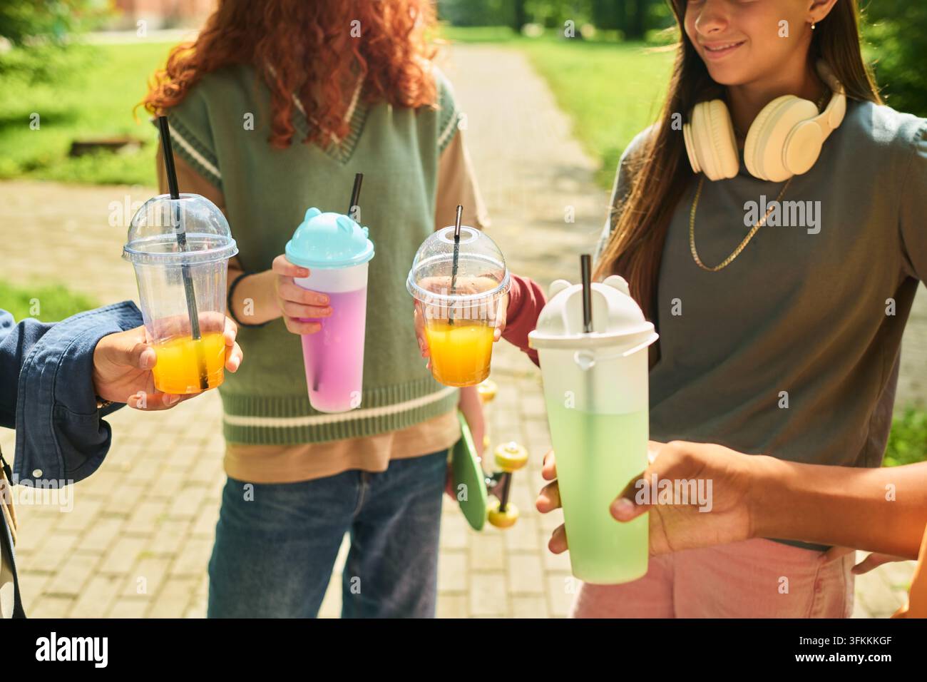 Amici adolescenti che tengono bevande rinfrescanti fredde all'aperto nel parco Foto Stock