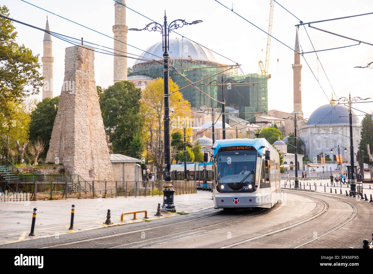 Istanbul, Turchia – 28 agosto 2026: Tram che passa accanto alla storica Hagia Sophia e a un antico monumento in pietra a Istanbul, Turchia, con lavori di costruzione Foto Stock