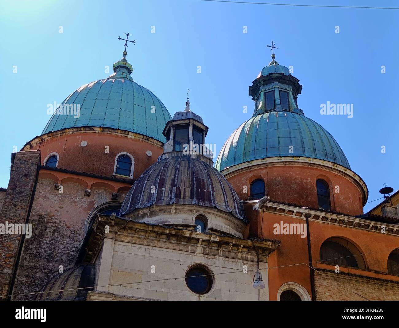 Cupole di rame e dettagli architettonici della storica cattedrale del Duomo contro un cielo blu terso a Treviso, Italia Foto Stock