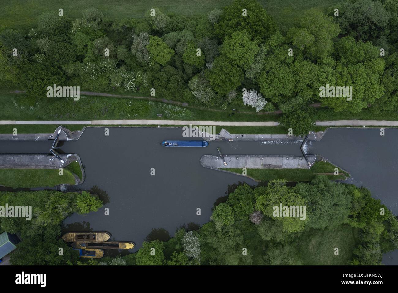 Vista aerea delle Hatton Locks sul Grand Union Canal con una narrowboat che naviga nel sistema di chiuse, circondata da rigogliosi alberi verdi e vegetazione a Ha Foto Stock