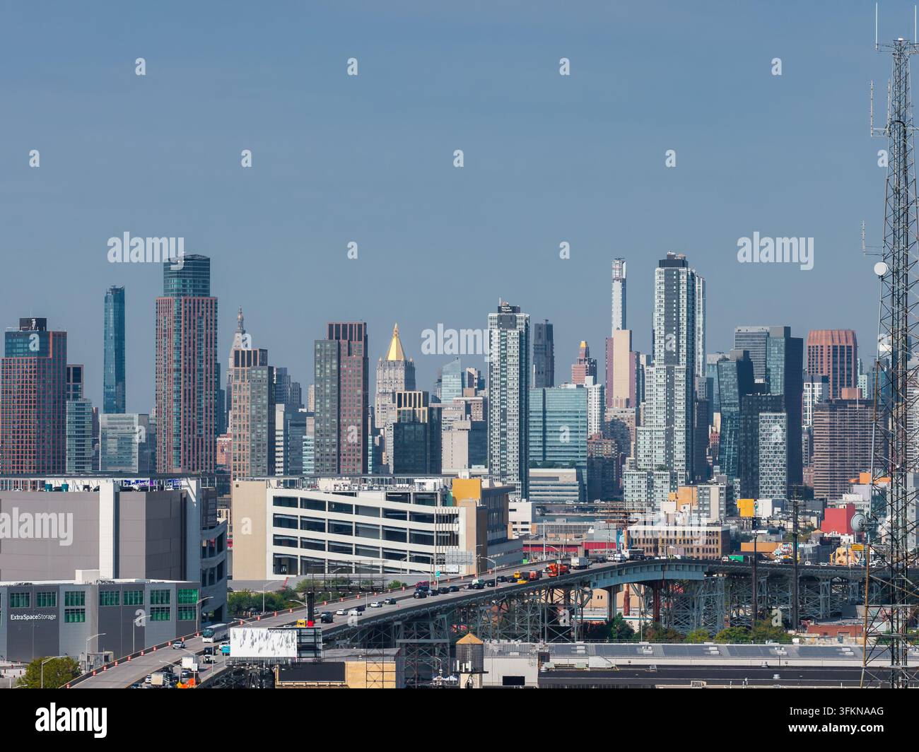 Veduta aerea che cattura il traffico lungo la rampa di accesso al ponte di Queensboro verso grattacieli moderni e torri residenziali sotto un cielo limpido s Foto Stock