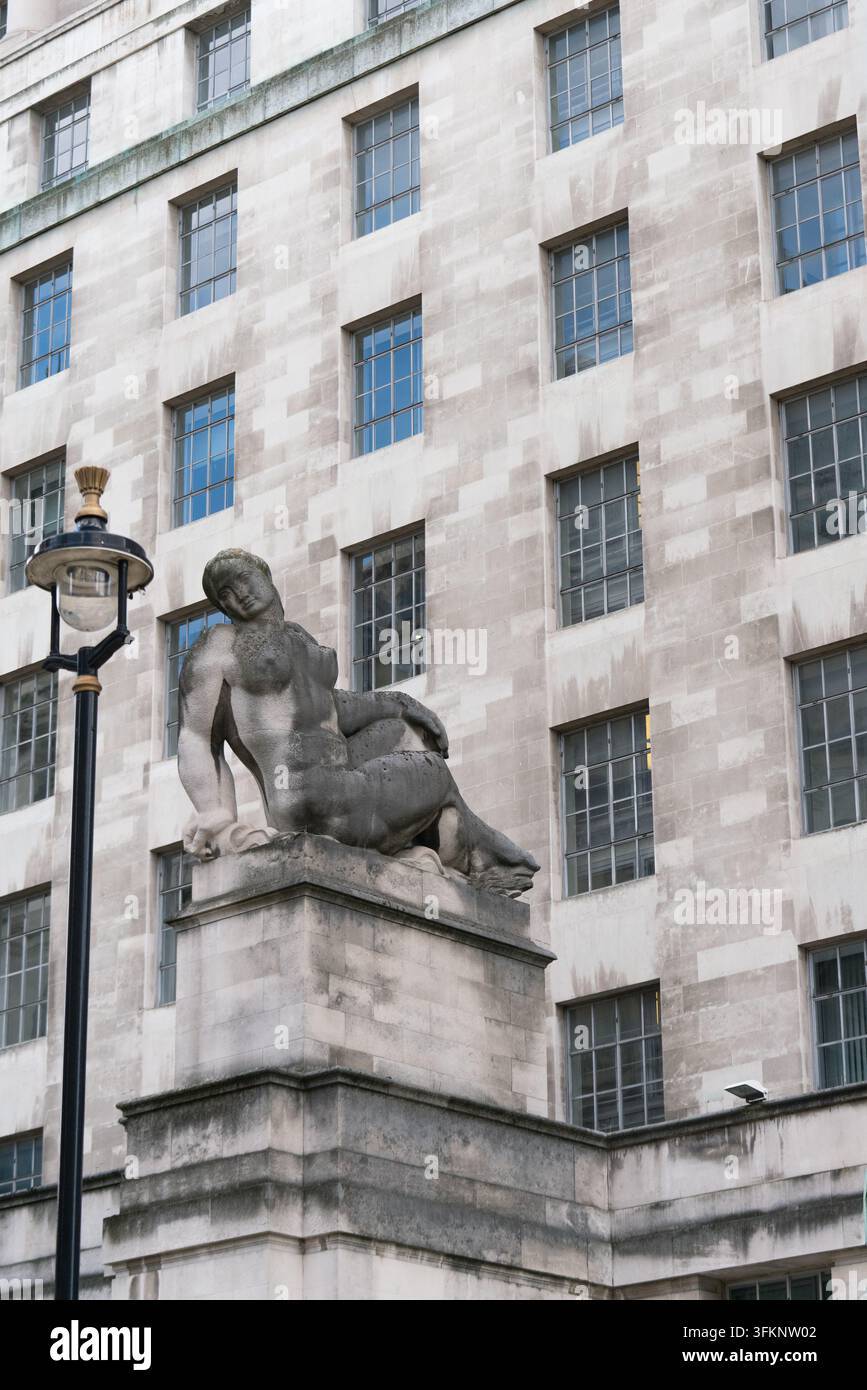 La scultura "Terra" di Eric Gill adorna la facciata del Ministero della difesa a Whitehall, Londra, servendo come arte architettonica decorativa. Foto Stock