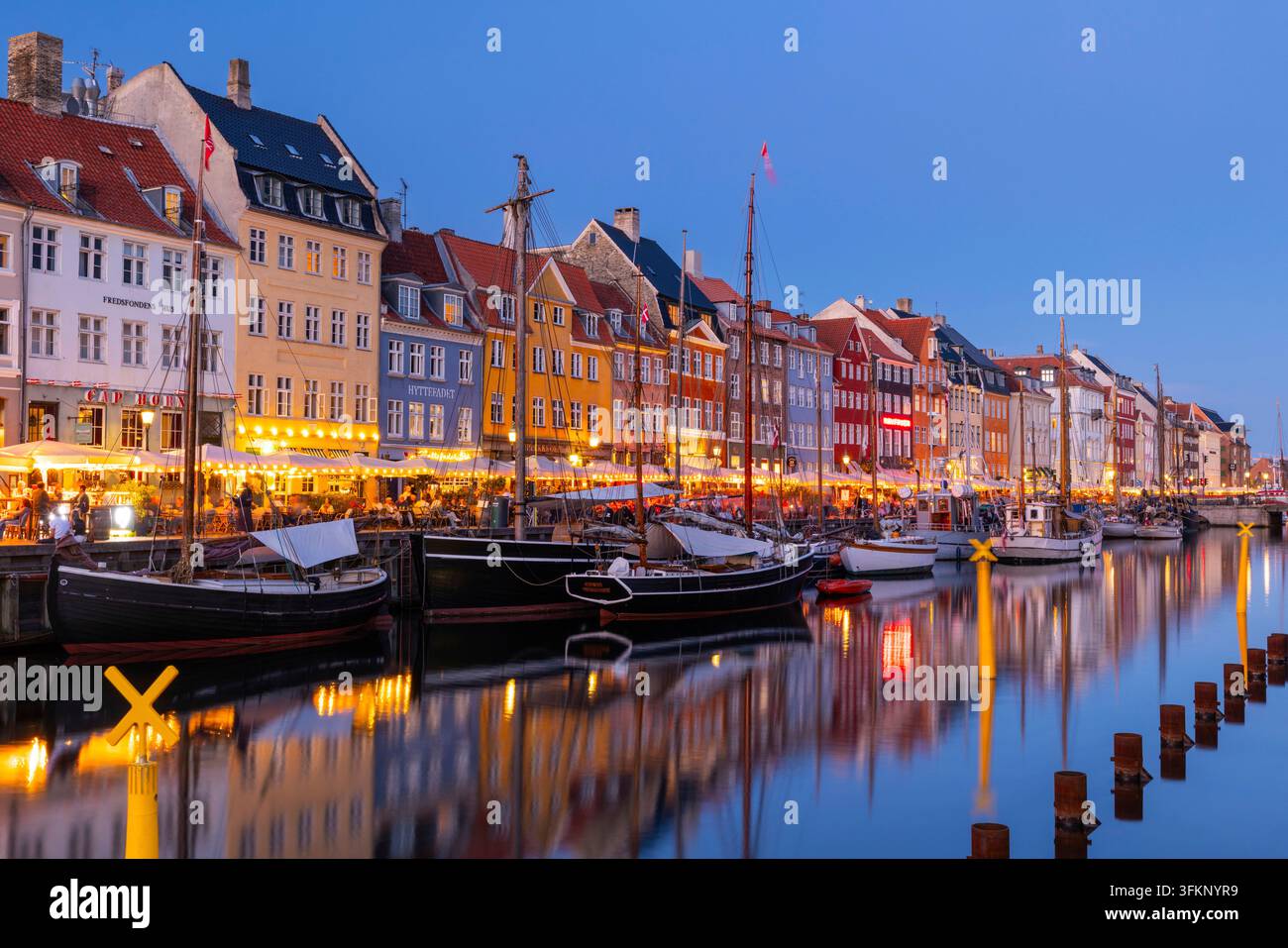 Barche davanti alle case dai tetti colorati di Nyhavn, ora blu, Copenaghen, Danimarca Foto Stock