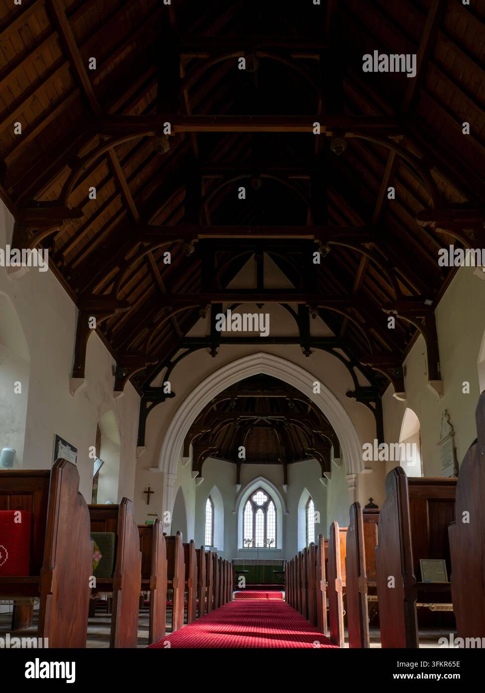20 settembre 2026, Loweswater, Regno Unito. La luce del sole filtra attraverso le finestre ad arco di una chiesa storica, illuminando la navata ricoperta da un tappeto rosso Foto Stock