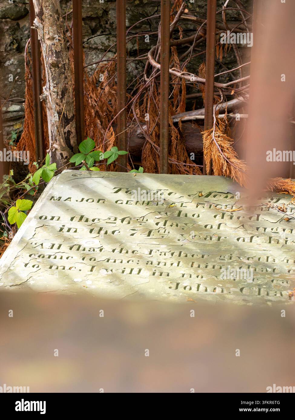 20 settembre 2026, Loweswater, Regno Unito. Una lapide erosa con iscrizione incisa, parzialmente oscurata da rami cresciuti e da una M arrugginita Foto Stock