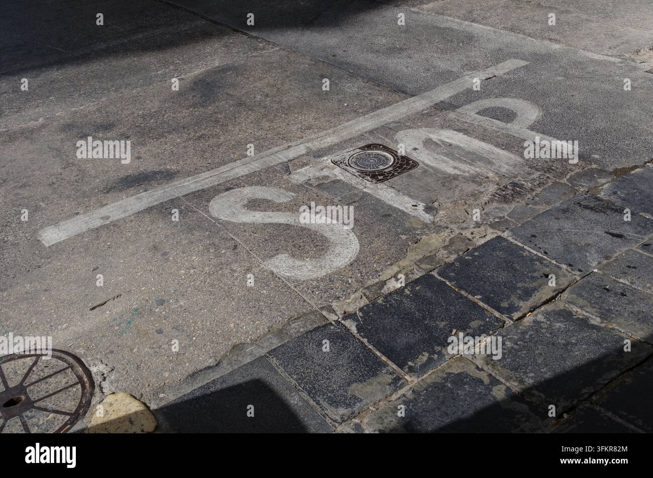 Un cartello di stop sbiadito dipinto in bianco sulla strada a un incrocio a Valletta, Malta Foto Stock