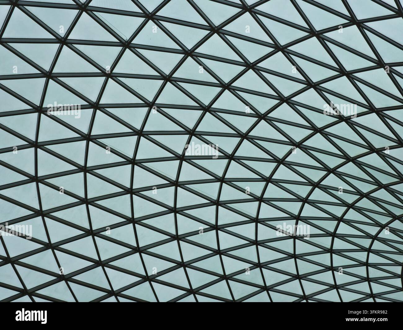 Struttura a tetto in vetro geometrica – Un motivo architettonico astratto di lastre di vetro triangolari e una cornice in metallo scuro crea un soffitto moderno e futuristico Foto Stock