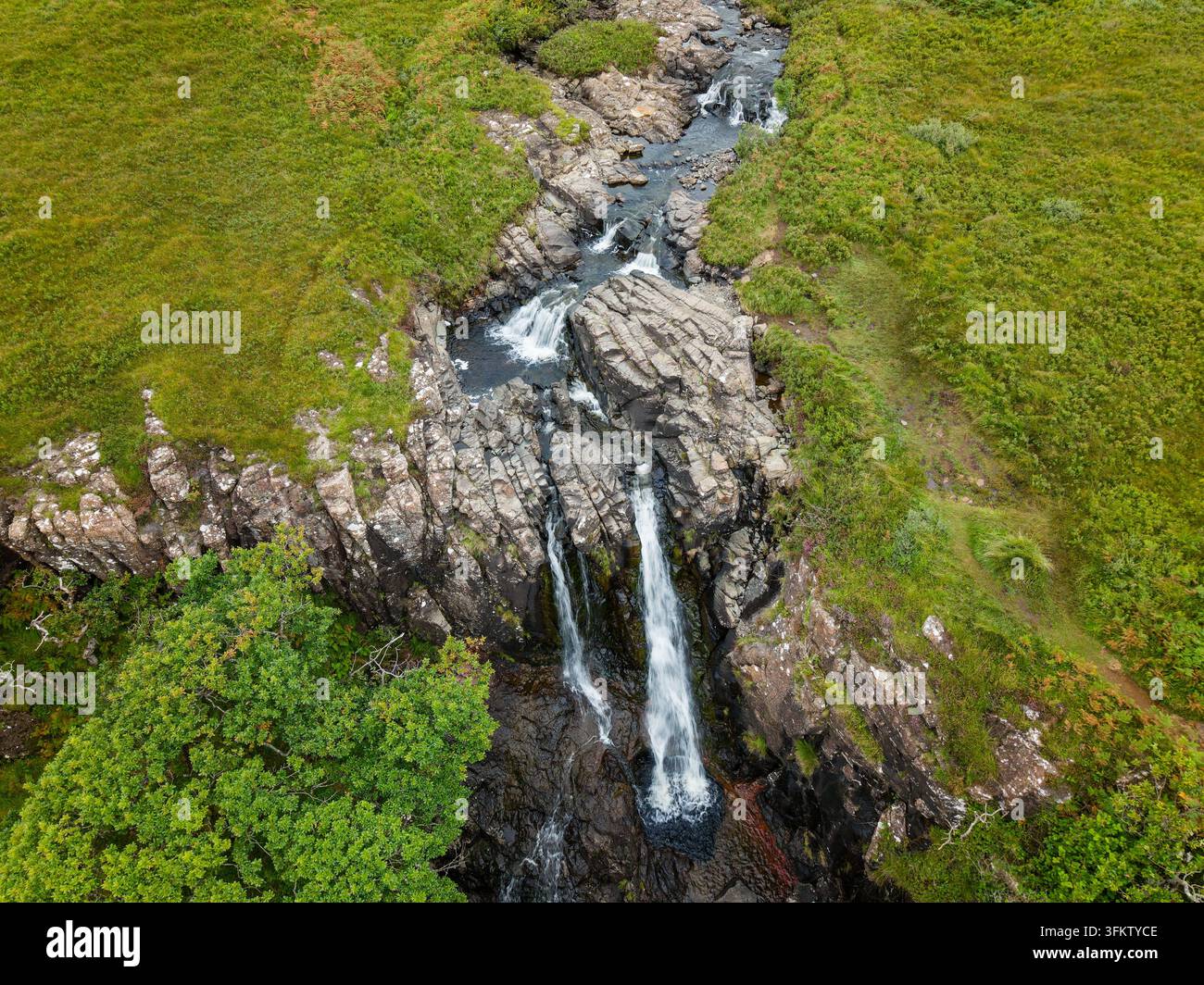 Vista aerea della cascata di Eas Fors sull'Isola di Mull, Scozia, acqua che scorre su sporgenze rocciose scure in una gola circondata da pendici erbose Foto Stock