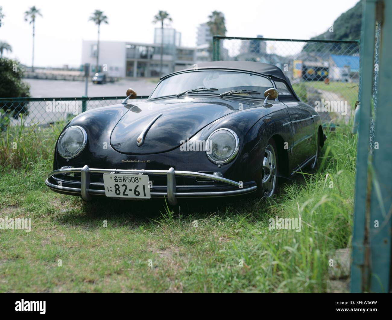Porsche 356 nero classico parcheggiato sull'erba costiera con palme ad Aichi, Giappone Foto Stock