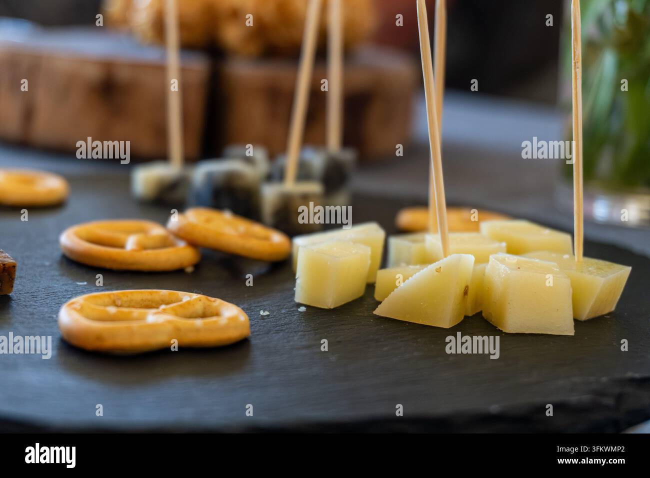 Tagliere di formaggi con pretzel e spiedini su ardesia scura Foto Stock