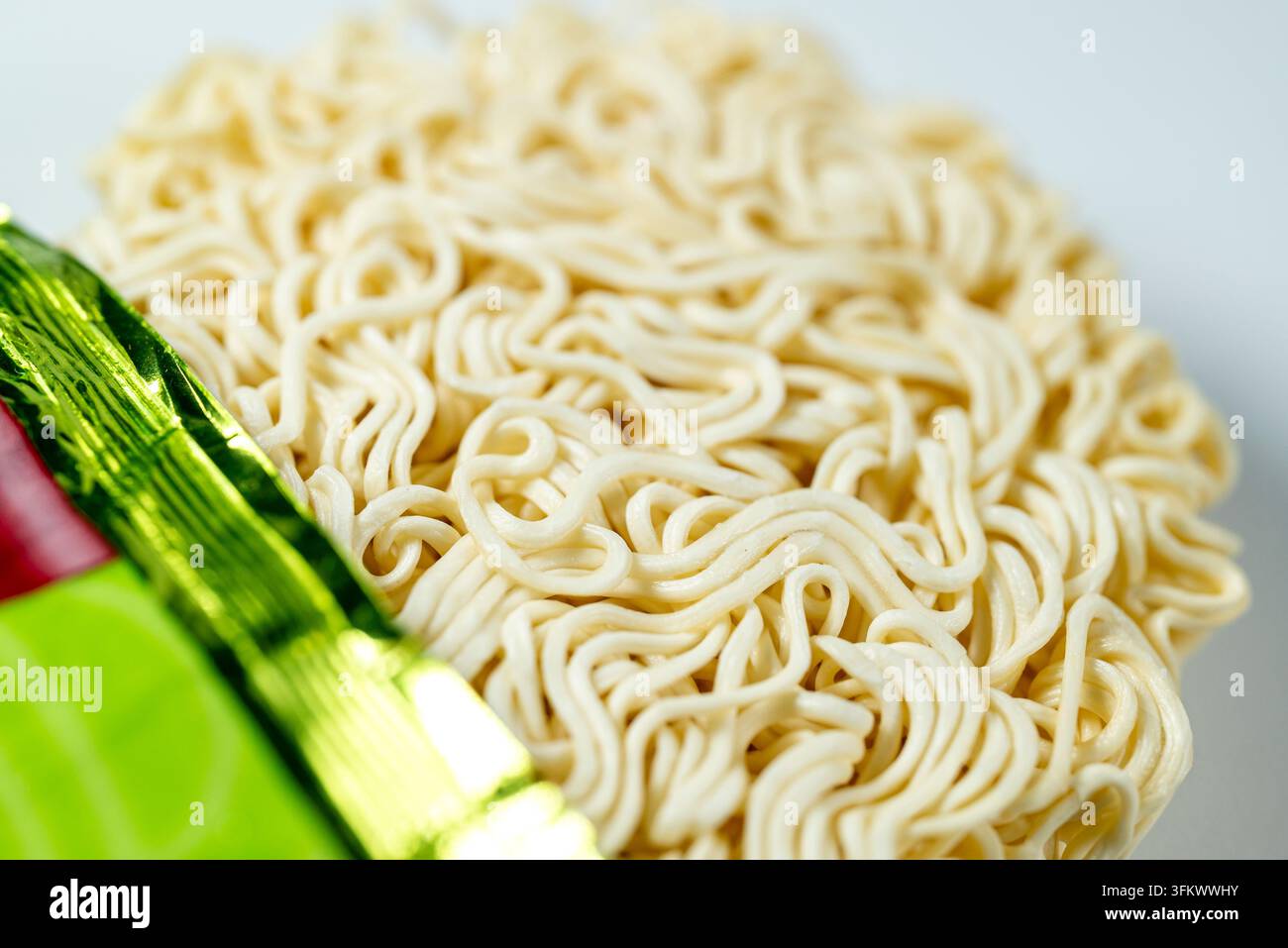 Vista macro di un blocco di noodles istantanei ricci non cotti Il concetto di cibo di convenienza e pasto veloce Foto Stock