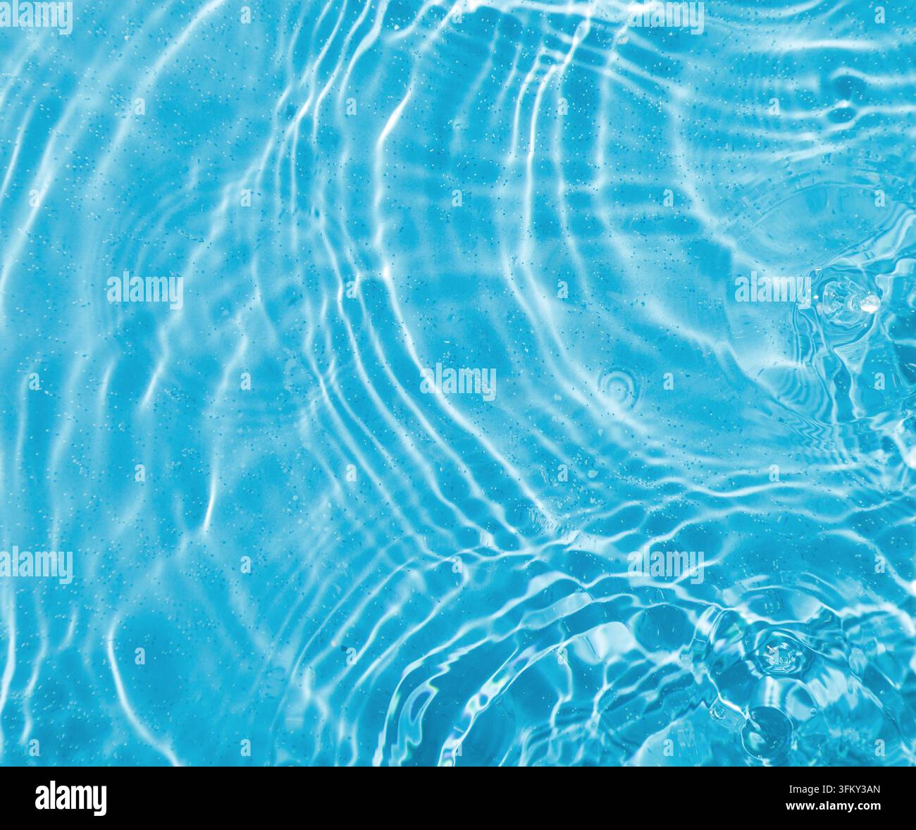 Gocce sull'acqua con cerchi su sfondo blu primo piano Foto Stock
