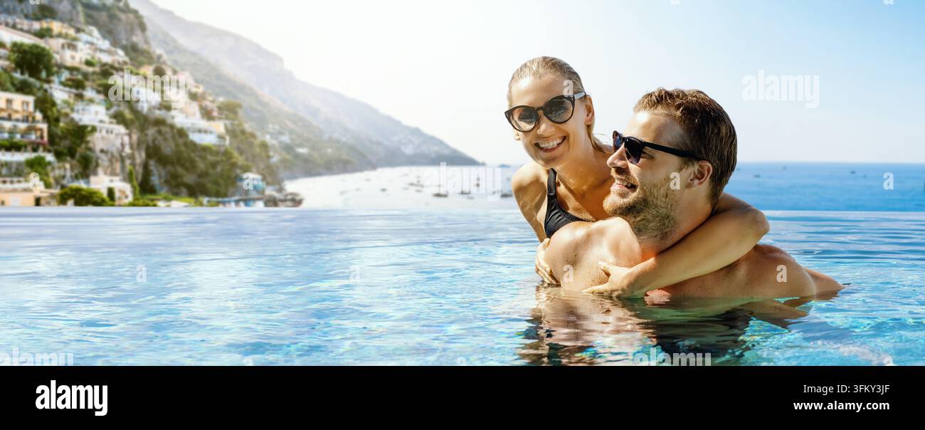 Coppia che si diverte insieme in una piscina a sfioro con vista sul mare e la città di Positano sullo sfondo. Vacanza estiva romantica in Italia. Viaggio di nozze. Foto Stock