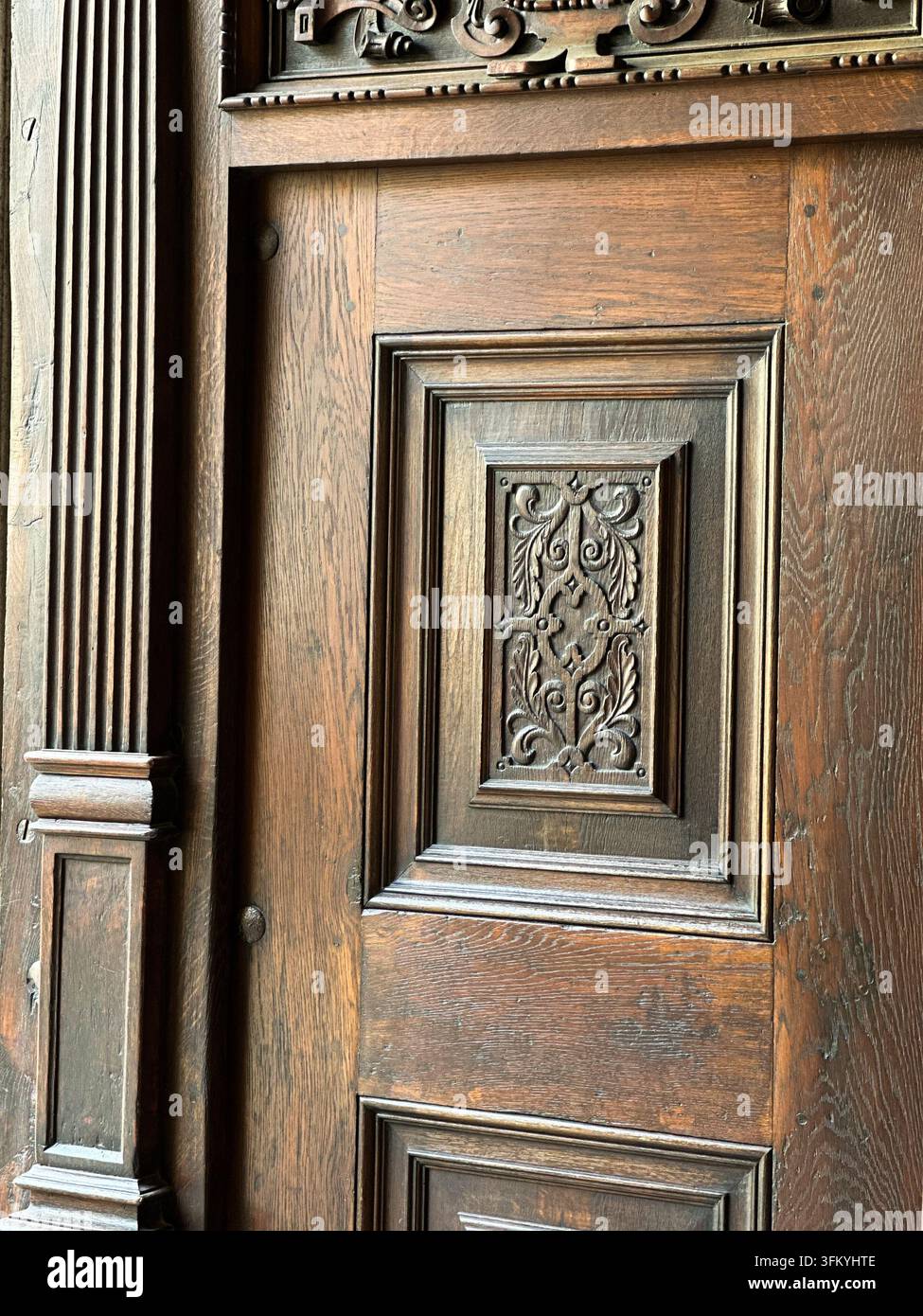 Prima piano di un pannello di porta in legno antico finemente intagliato. Una dettagliata ripresa in primo piano di una porta in legno antica con un motivo a rilievo scolpito ornato - Immagine stock catturata con smartphone