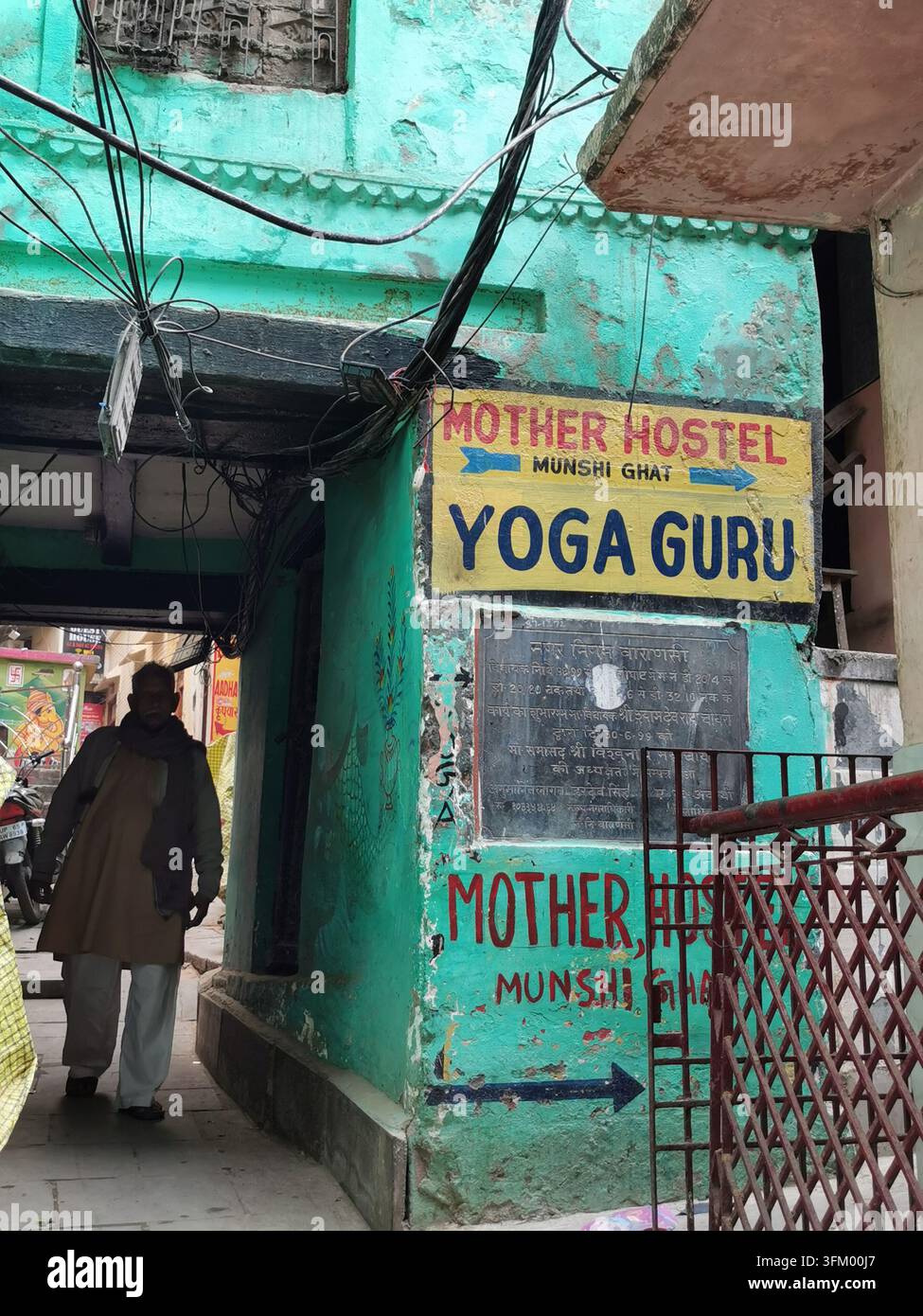 VARANASI, INDIA - 23 GENNAIO 2026: Un cartello dipinto a mano pubblicizza un ostello e corsi di yoga vicino a Munshi Ghat. Foto Stock
