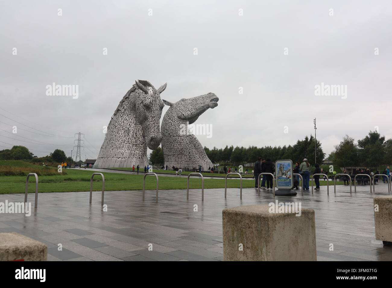 Turisti alle imponenti sculture delle teste di cavallo Kelpies a Falkirk, in Scozia, in una piovosa giornata uggiosa. Foto Stock