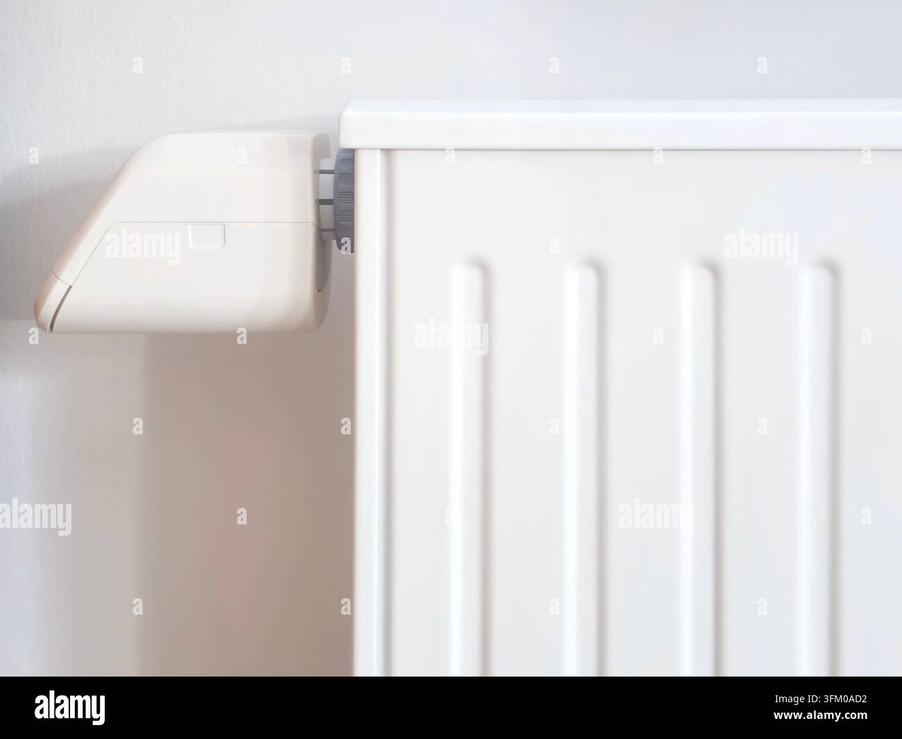 Radiatore bianco di riscaldamento centralizzato montato su una parete chiara all'interno, vista ravvicinata del moderno sistema di riscaldamento domestico con valvola termostatica in un ambiente residenziale - Immagine stock catturata con smartphone