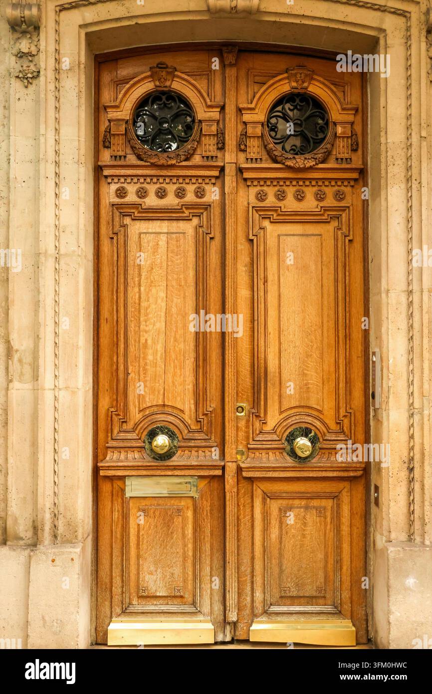 Elegante porta in legno con intagli dettagliati, griglie in ferro battuto, pomelli in ottone e una tradizionale fessura postale a Parigi Foto Stock
