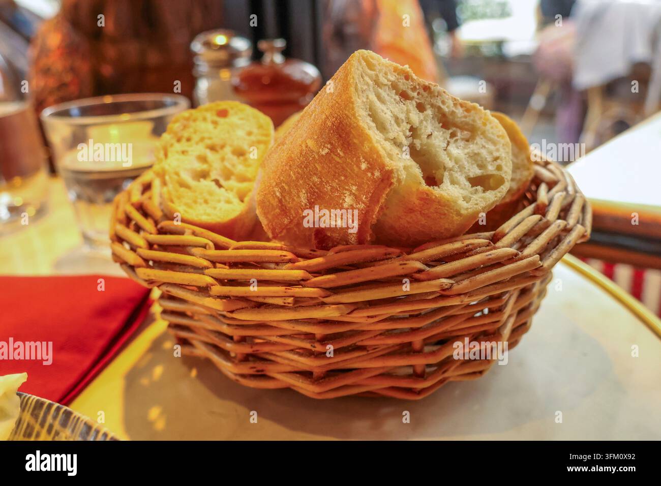 Fette di baguette appena sfornate servite in un cestino intrecciato su un tavolo da bistro, creando un'esperienza di viaggio e di pasto autentico Foto Stock