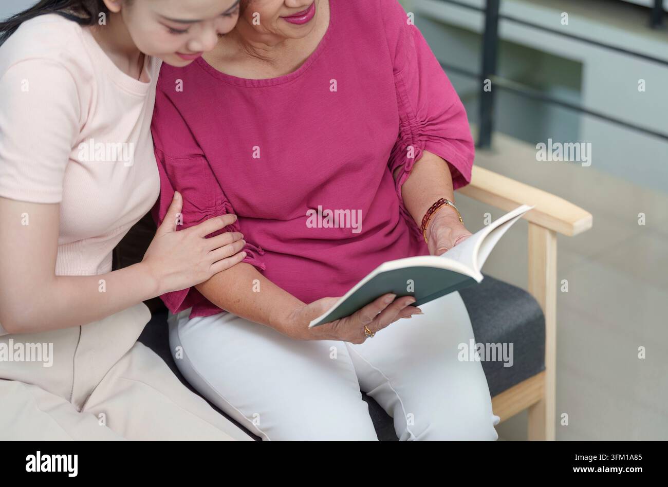 Una madre e una figlia condividono un momento tranquillo leggendo un libro insieme, simboleggiando amore, apprendimento e connessione nel giorno della festa della mamma Foto Stock