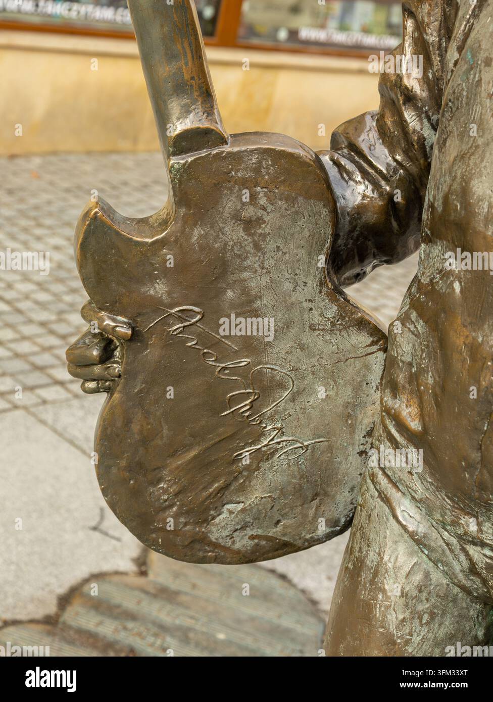 Primo piano della firma dello scultore sulla chitarra di bronzo della statua di Tadeusz Nalepa a Rzeszow. Foto Stock