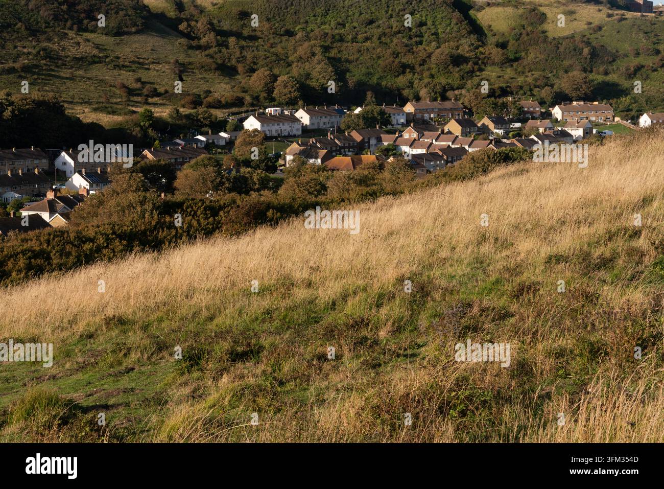 Escursionisti sull'England Coast Path osservano il villaggio di East Dean incastonato nei South Downs per un'esplorazione costiera scenografica. Foto Stock