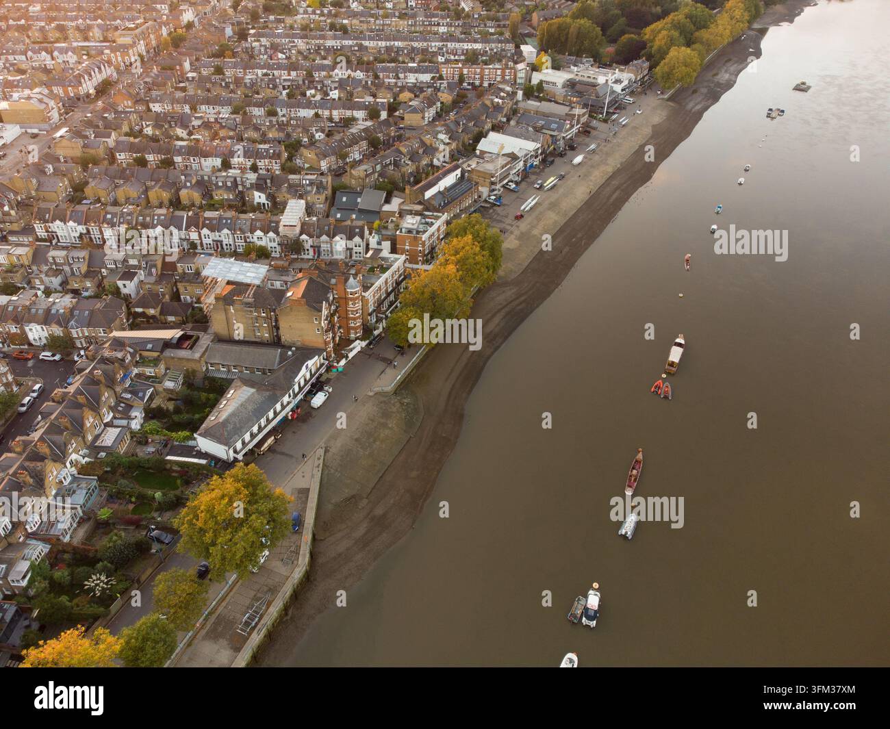 I diportisti ormeggiano le loro imbarcazioni lungo il Tamigi durante la bassa marea, mettendo in mostra l'argine fluviale di Putney a Wandsworth, Londra. Foto Stock