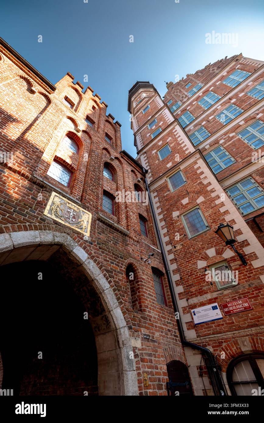 Vista ad angolo basso del portale in mattoni Mariacka e dell'edificio storico adiacente sul lungomare. Foto Stock