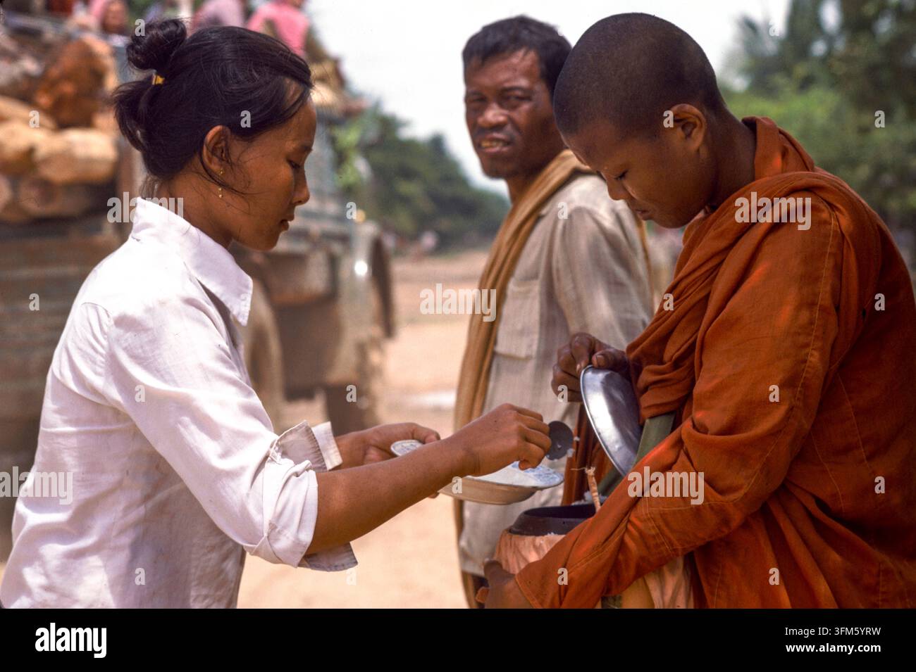 Una donna che dà cibo e riceve una benedizione da un monaco buddista, Cambogia rurale, 1987 Foto Stock