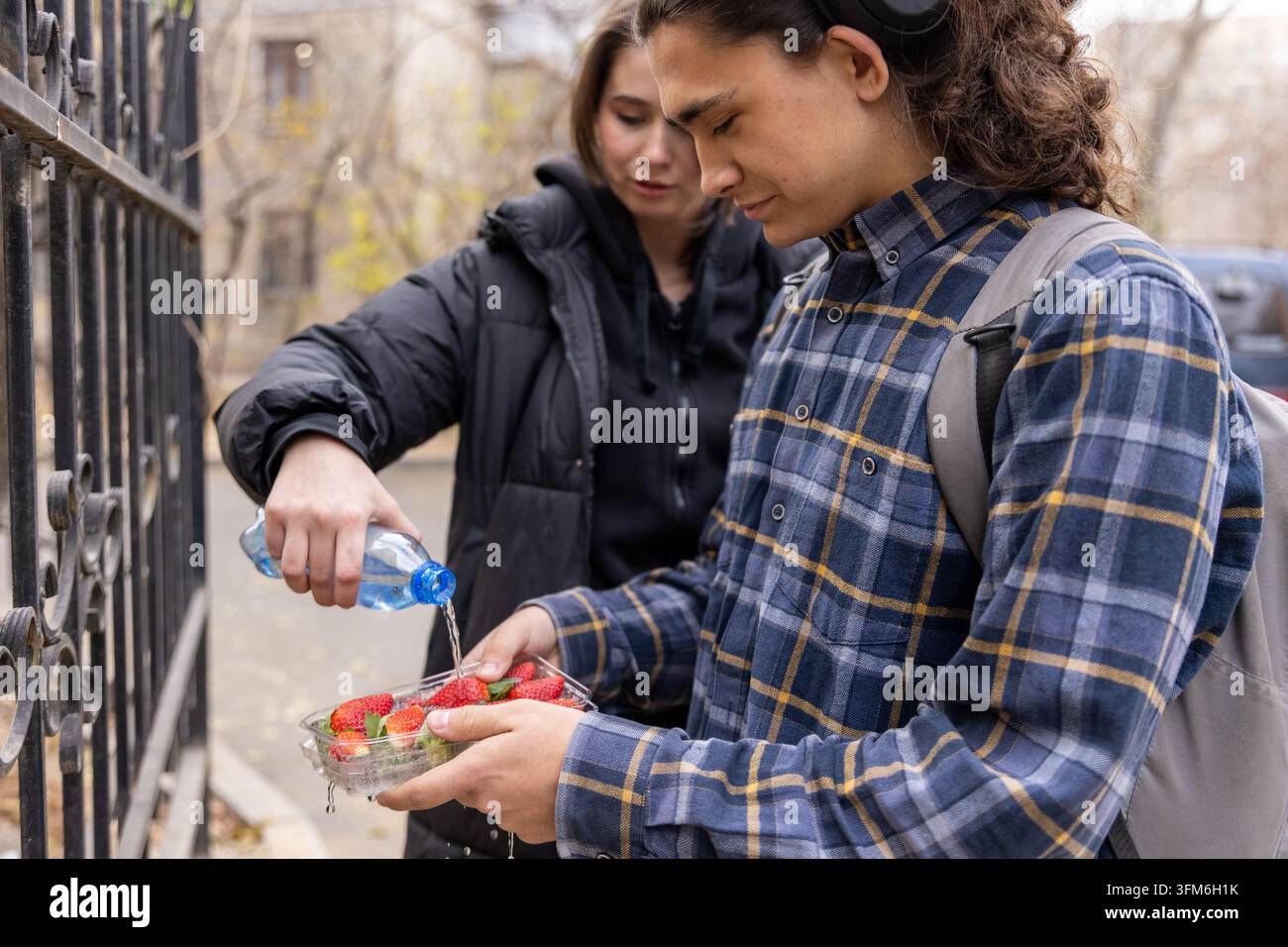 Studenti che lavano le fragole con acqua in bottiglia Foto Stock